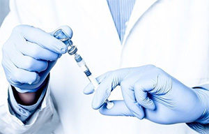 врач набирает в шприц вакцинный препарат