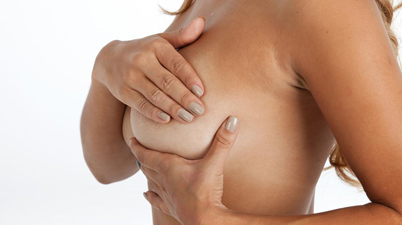 Женщина проверяет свою грудь на возможные осложнения при грудном имплантате